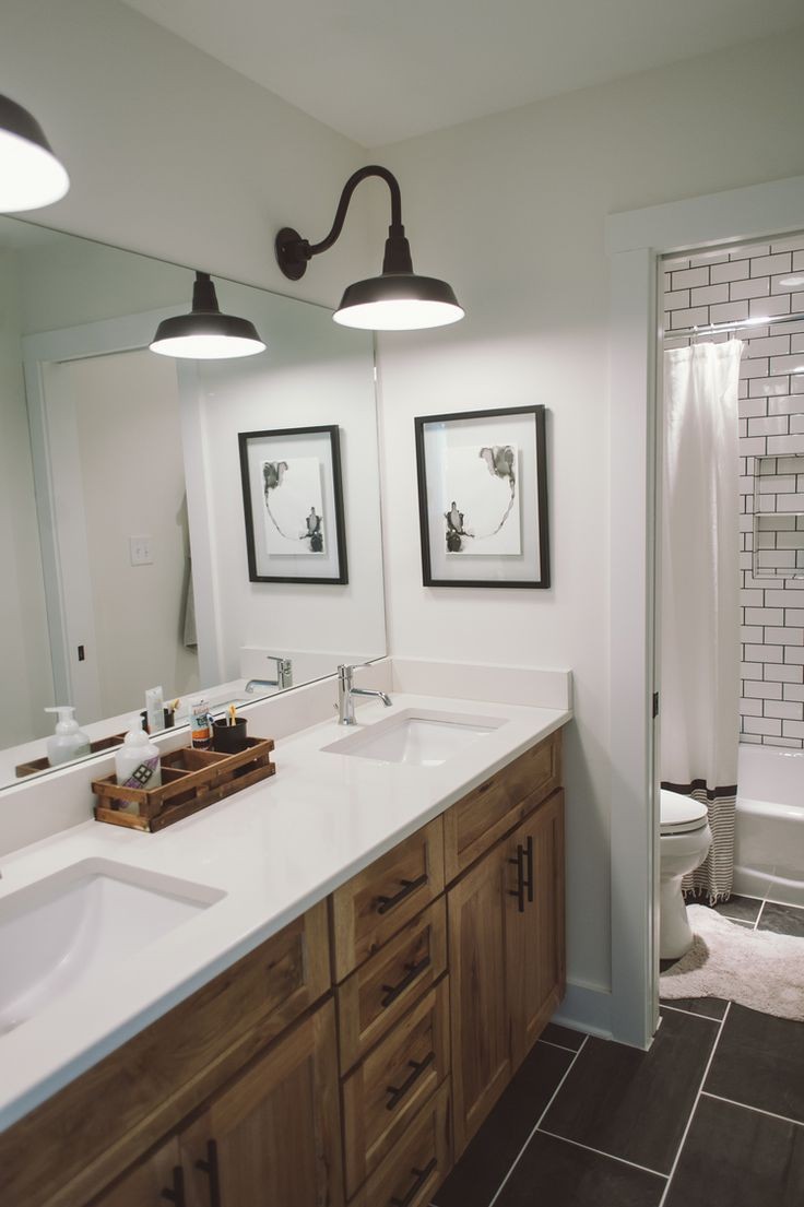 stained cabinetry modern pulls clean white counters and undermount sinks black tile with white grout farmhouse sconces